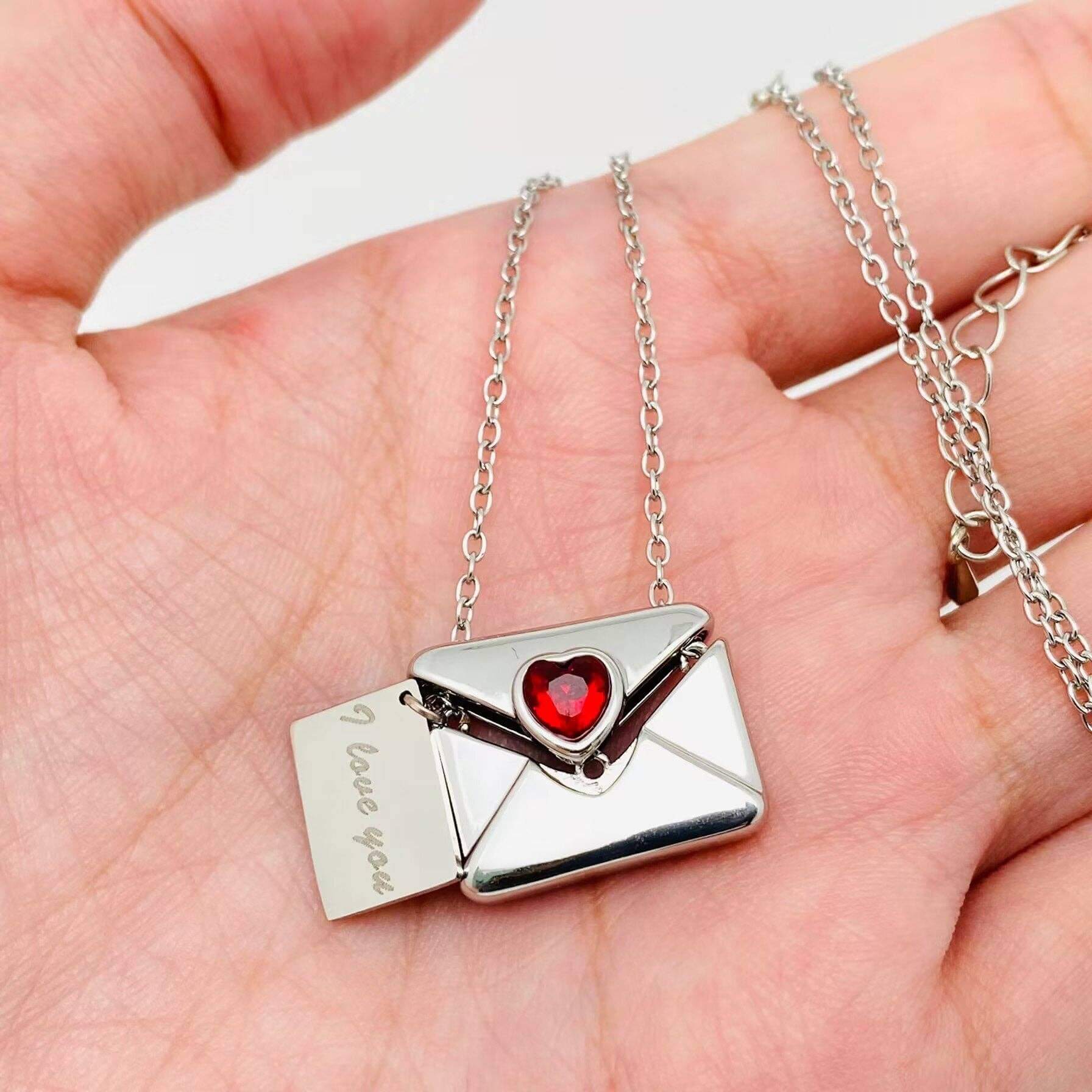 Close-up of the LOVE LETTER NECKLACE featuring an envelope pendant with a heart-shaped gem and an engraved message.