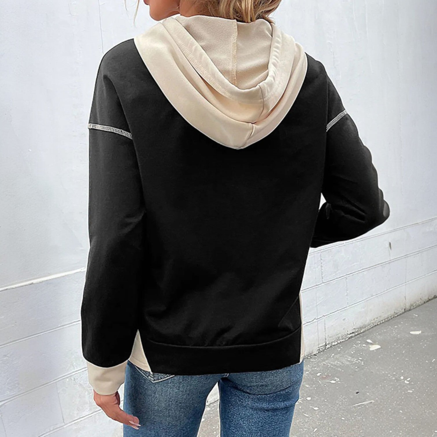 Back view of a woman wearing the MODERN EDGE HOODIE featuring black and beige color block design.