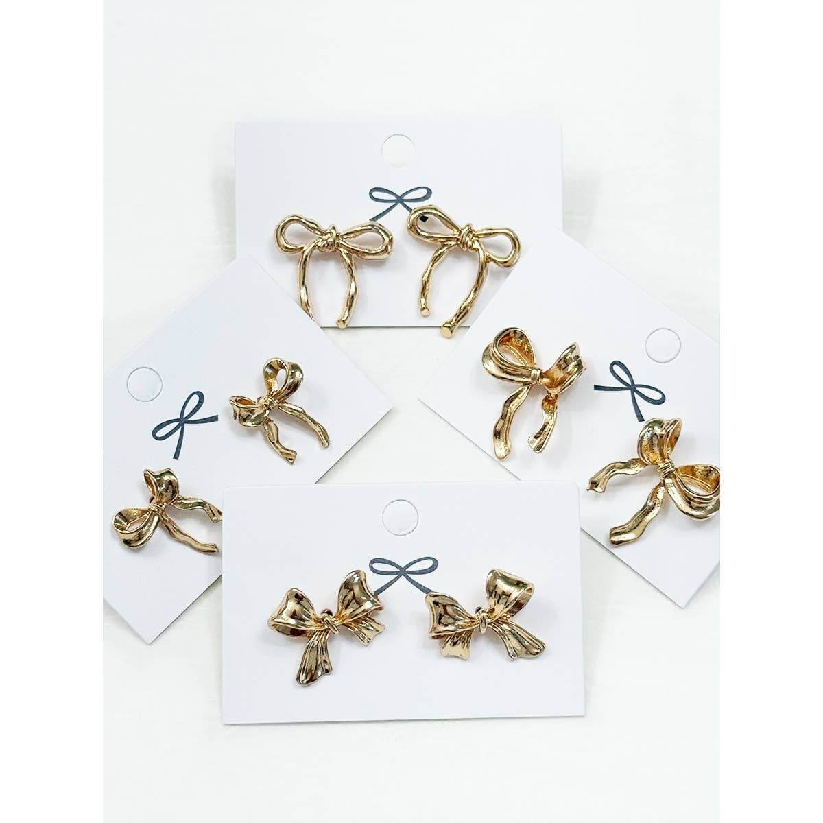Gold bow earrings in four unique styles displayed on cards for feminine flair by Love and Repeat.