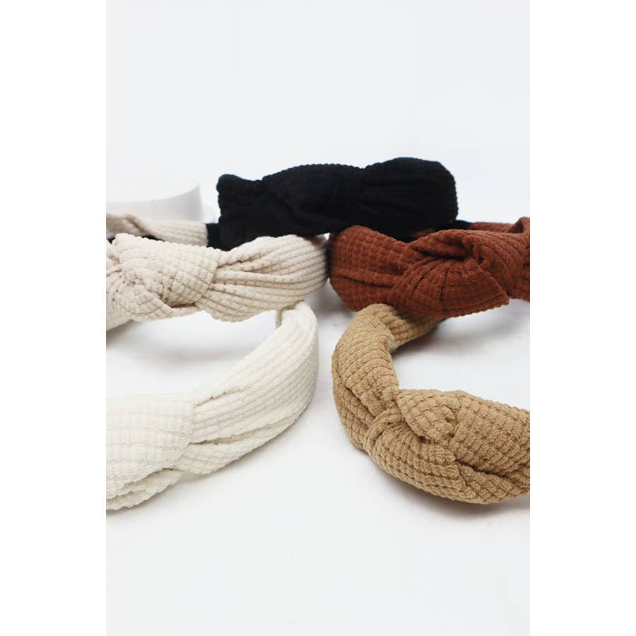 Five stylish knit headbands in neutral tones: black, brown, beige, and cream showcasing cozy texture and fashion.