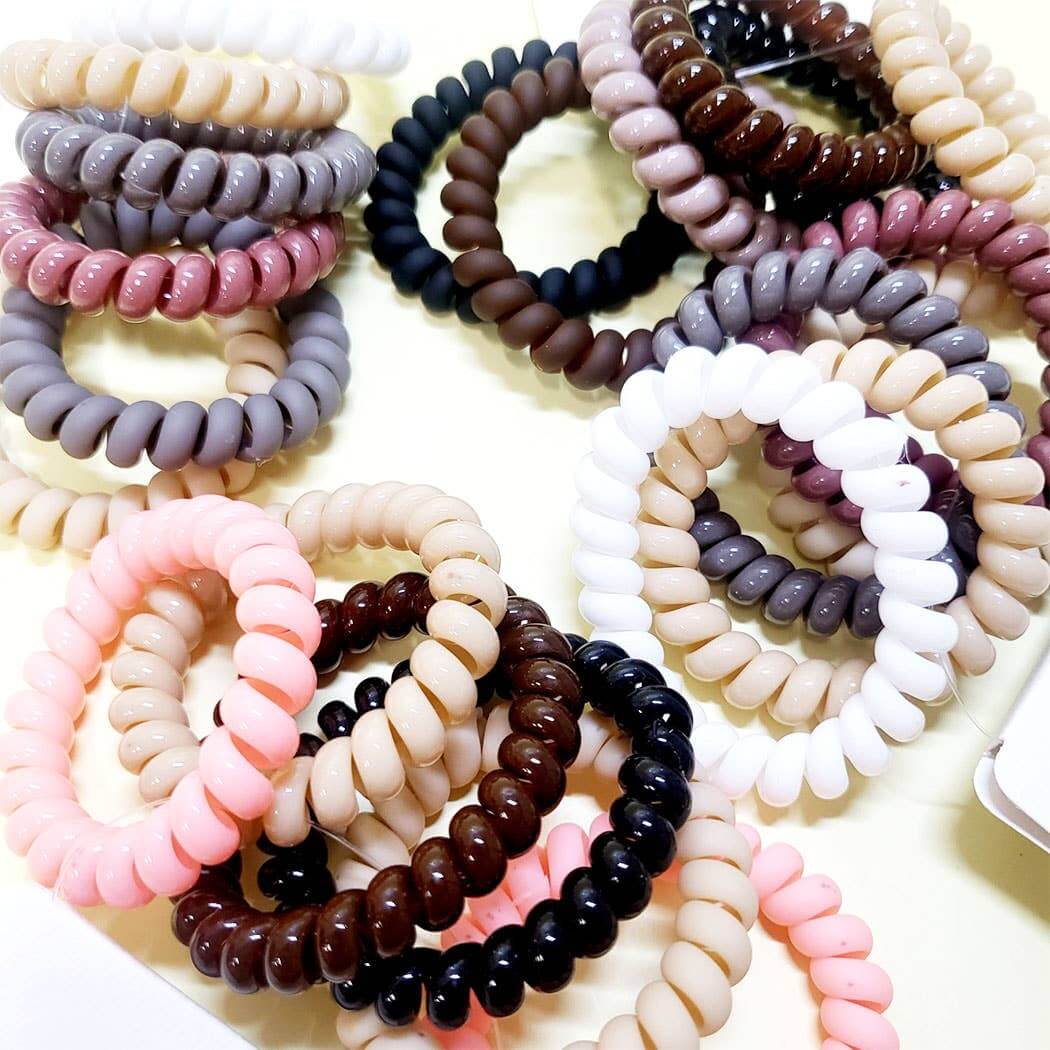Assorted twist and tell hair ties in neutral and pastel tones, showcasing smooth, stretchy coil design for secure hold.