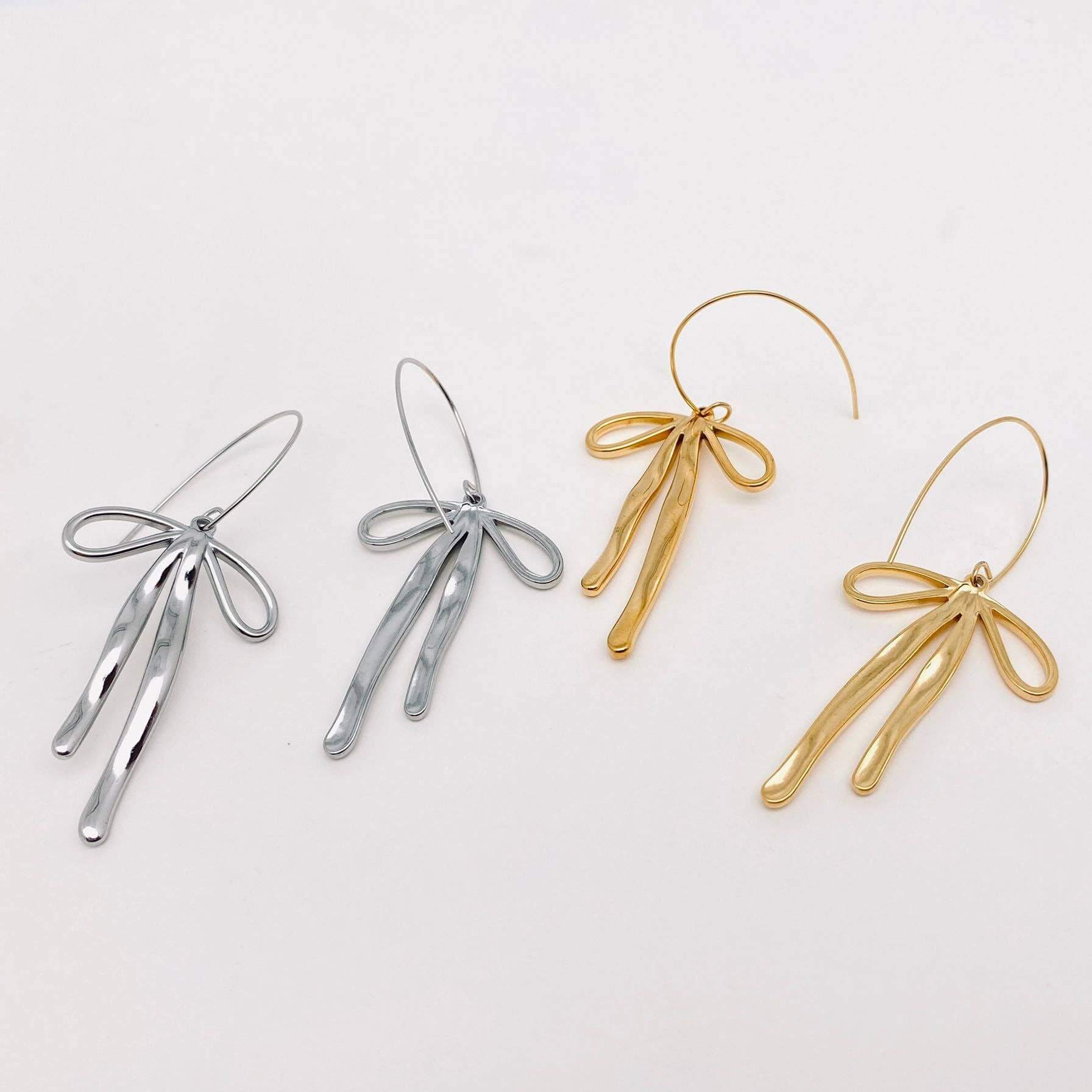 REFIEND RIBBON EARRINGS (2 colors) displayed in silver and gold with delicate bow-inspired designs.