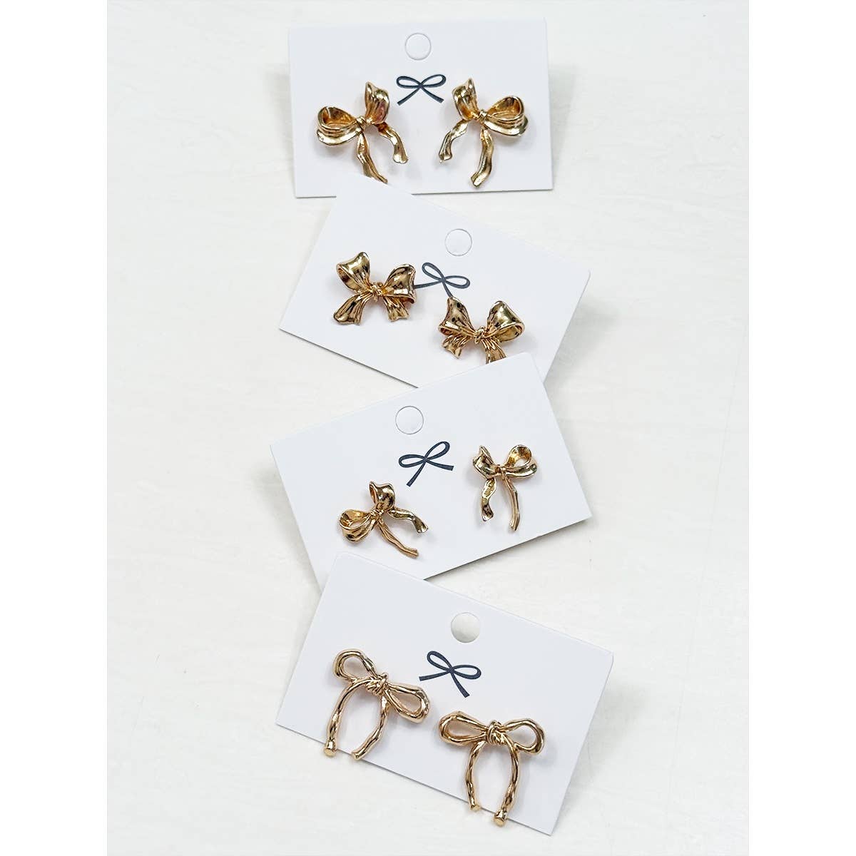 Bows Before Beaus gold bow earrings in four styles by Love and Repeat on display.
