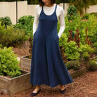 Model wearing EVERY DAY ESCAPE JUMPSUIT in a garden, showcasing its flowy wide-leg silhouette and keyhole back.