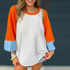 CITRUS CRUSH TOP in vibrant color block design featuring tangerine sleeves, sky blue cuffs, and a light grey body.