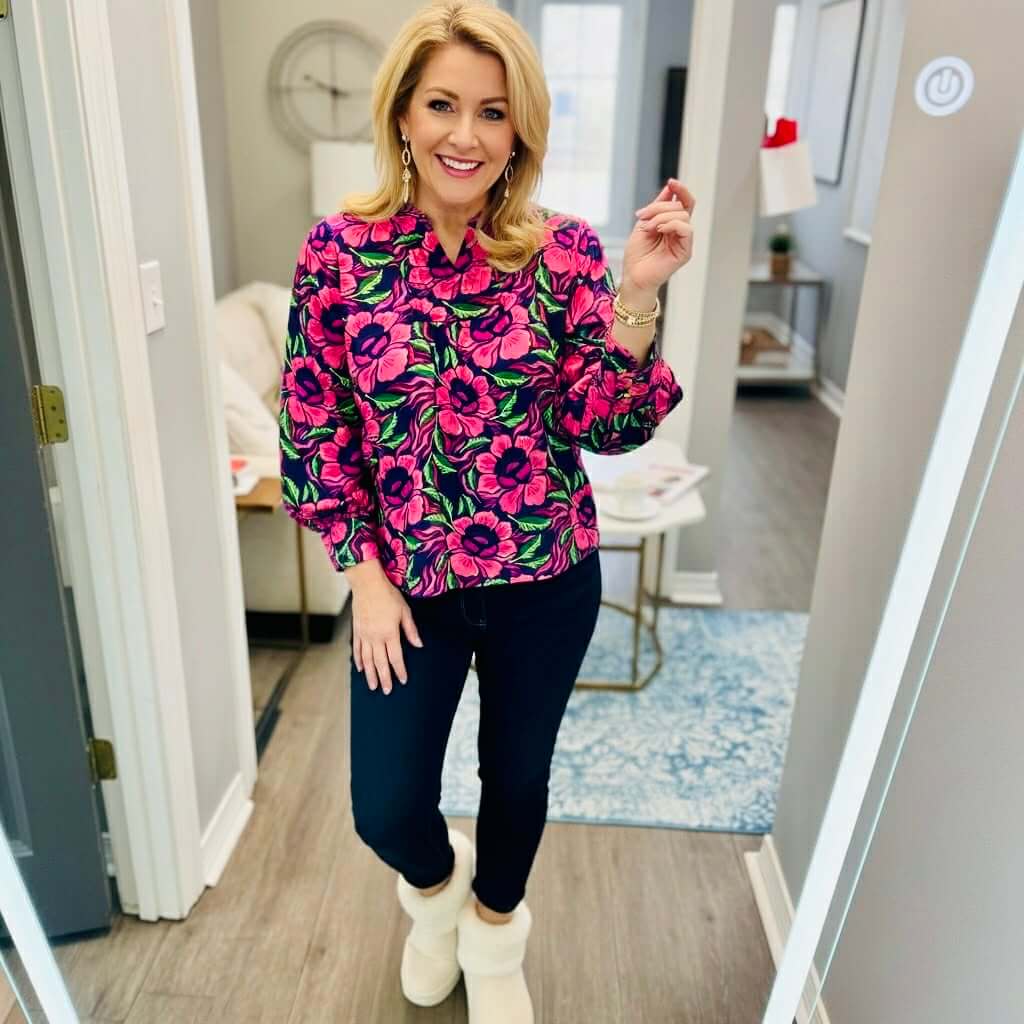 Woman wearing the SIENNA LOVESTRUCK TOP by Michelle McDowell with pink floral print and navy pants.