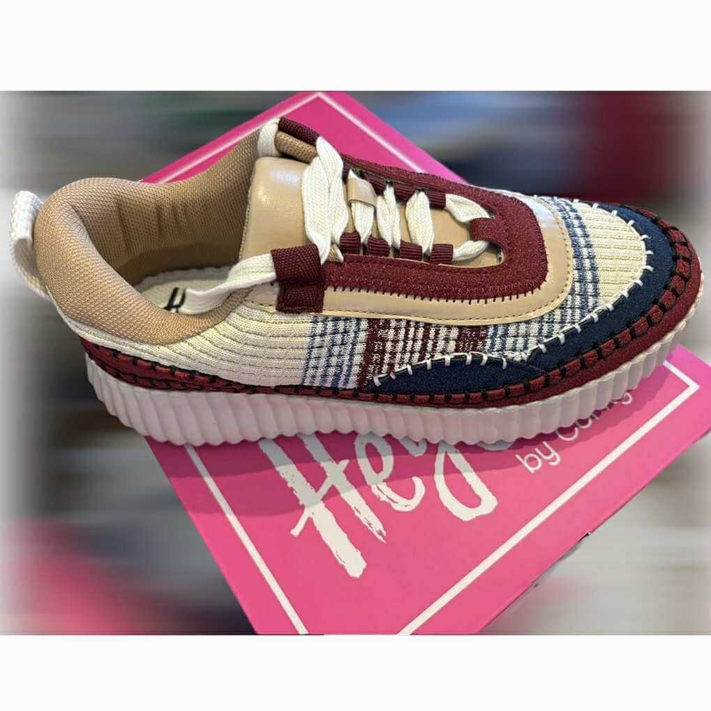 Corkys Adventure Sneakers in burgundy and cream with whipstitch detailing on a pink box background.