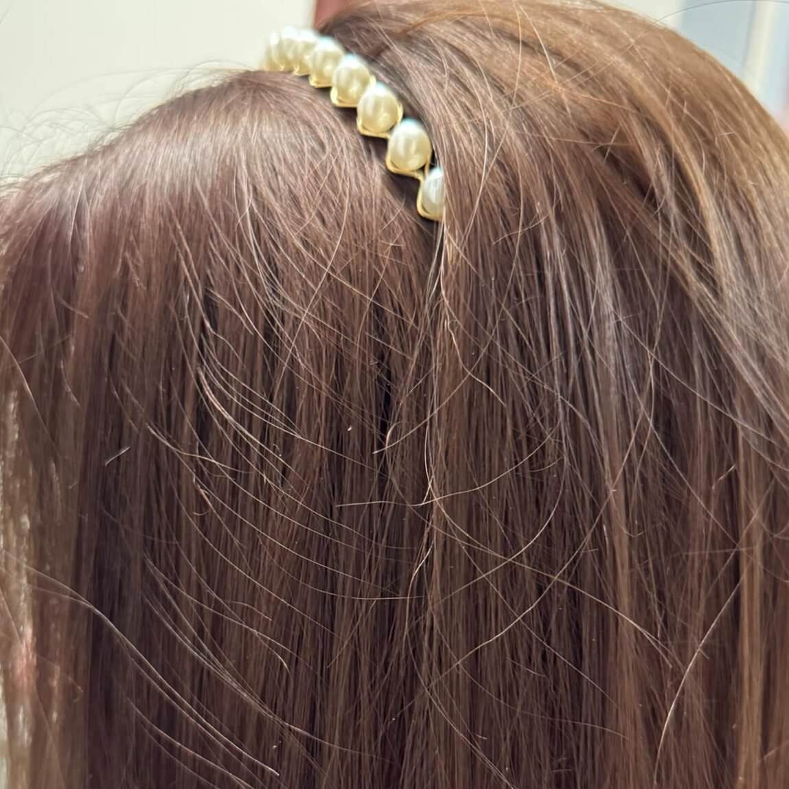 Close-up of a pearl embellished hairband worn on brown hair, adding elegance to any holiday outfit.