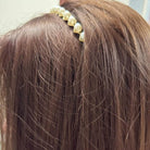 Close-up of a pearl embellished hairband worn on brown hair, adding elegance to any holiday outfit.