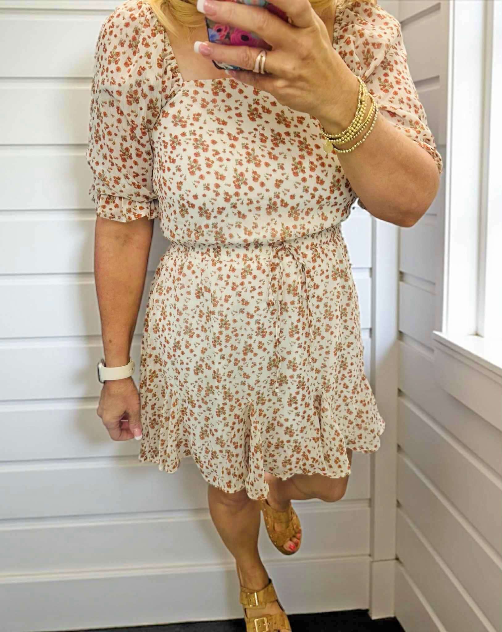 Woman wearing RUSTIC GRACE by Trixxi mini dress with floral print and smocked waist, styled for a chic summer look.