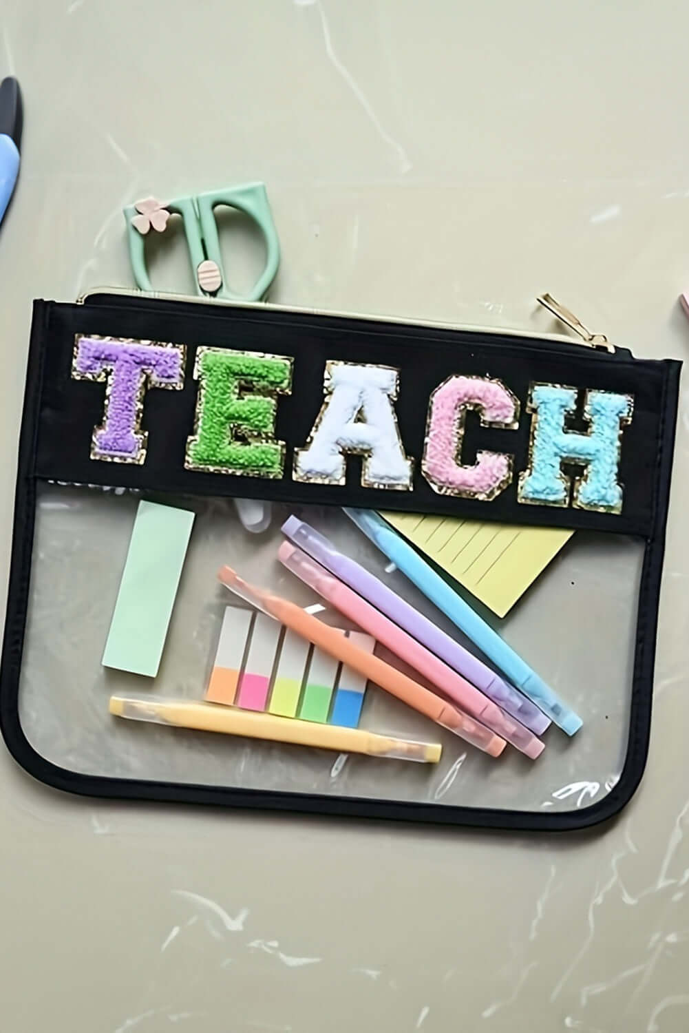 In My Teacher Era bag displaying 'TEACH' in glitter chenille, filled with colorful stationery and sticky notes.