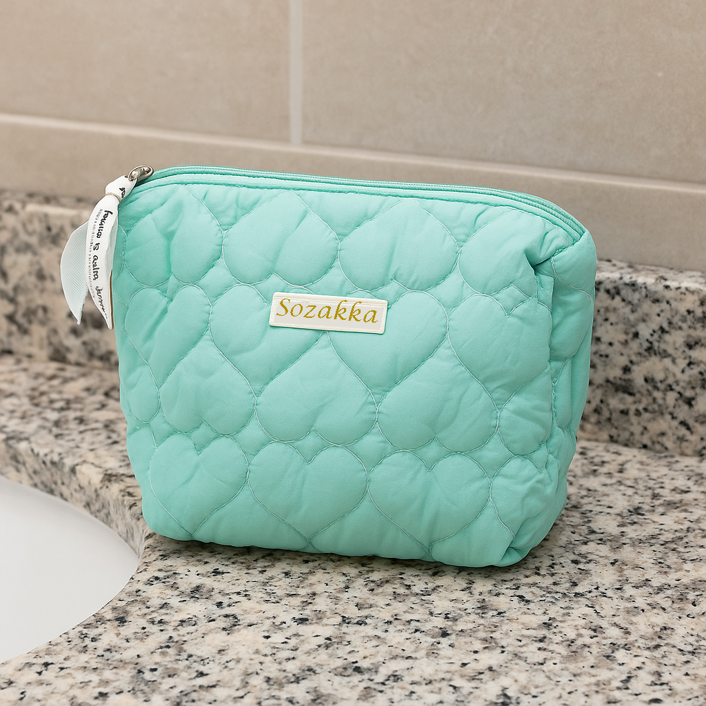 Aqua Blue heart-embossed quilted makeup bag by Sozakka on a granite counter.