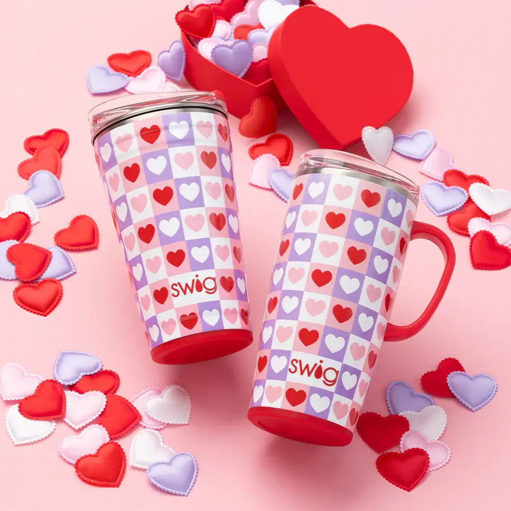 CHECK YES PARTY CUP- SWIG - Colorful checkered heart design party cups on a pink background with heart-shaped confetti.