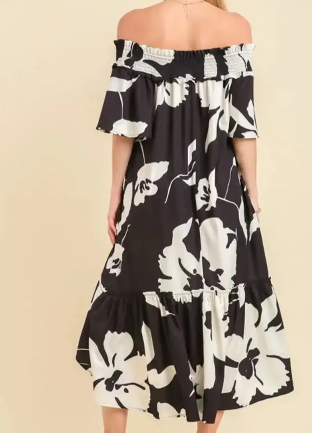 Elegant off-shoulder black floral Dreamways Dress with smocked bodice and flowing high/low midi length.