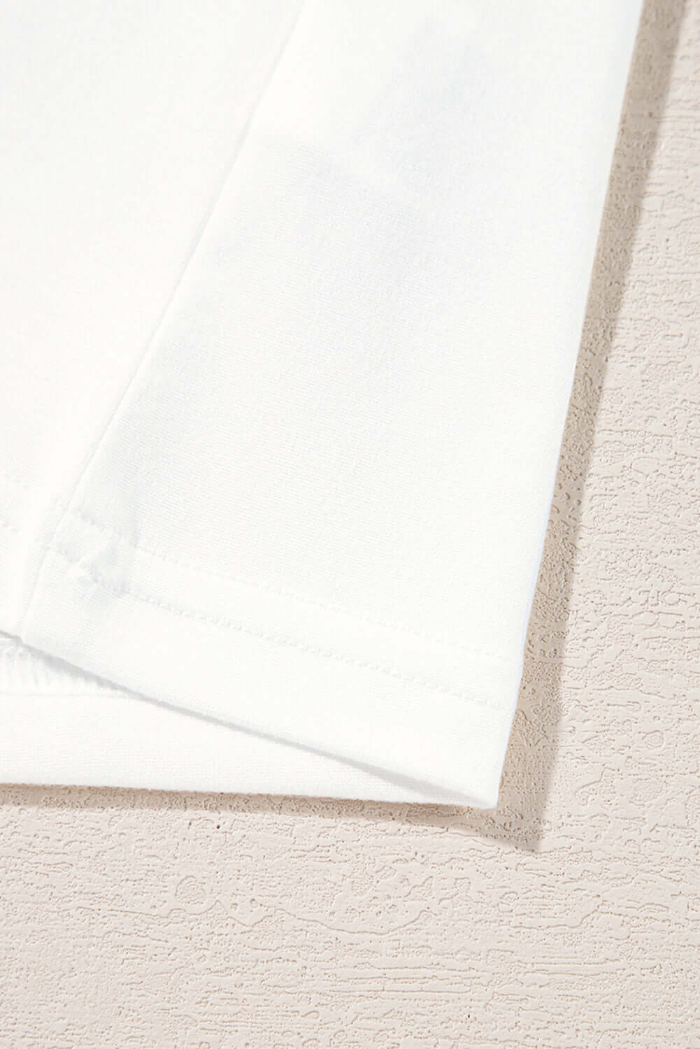 Close-up of a white fabric hem showing soft texture and clean stitching for stylish apparel.