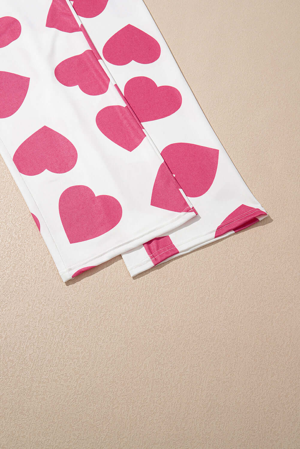 Pink heart-print lounge pants from the Love Language Lounge Set on a soft beige background.