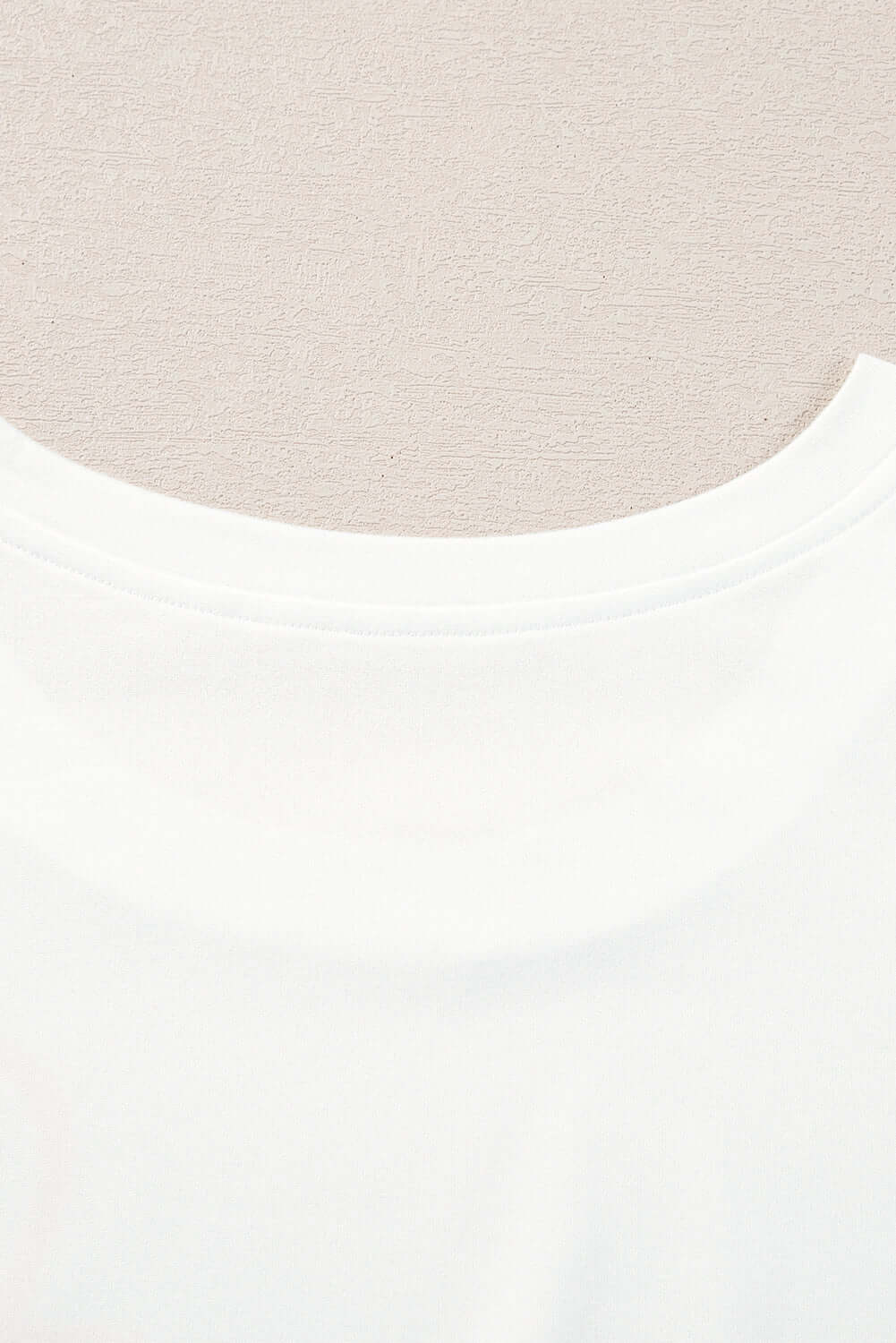 Close-up of white top's neckline, showcasing soft fabric and simple design for comfortable wear.