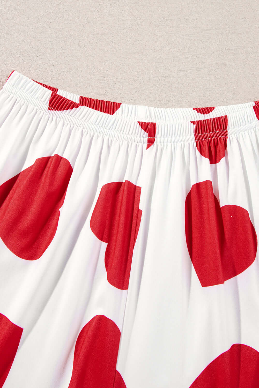 Detail of heart-print lounge pants from Love Language Lounge Set in red and white fabric.