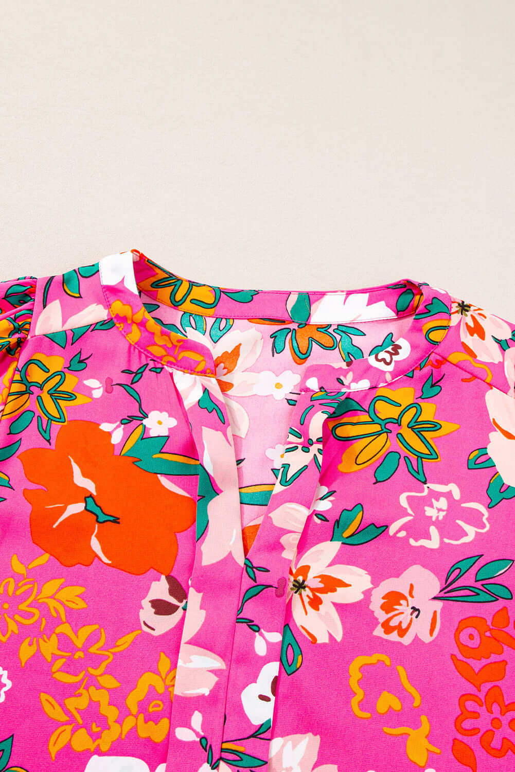 Vibrant rose floral printed blouse featuring split V-neckline and puff sleeves in pink and colorful blooms.