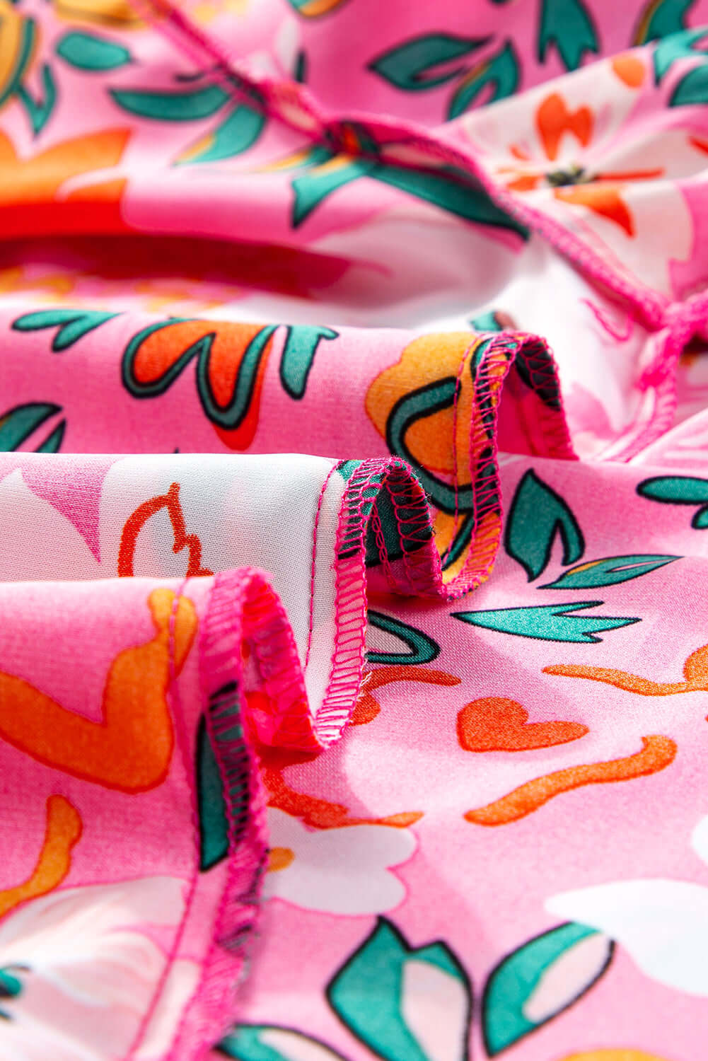 Close-up of vibrant pink floral fabric featuring tropical patterns and ruffled edges, ideal for Paradise Petals Top.