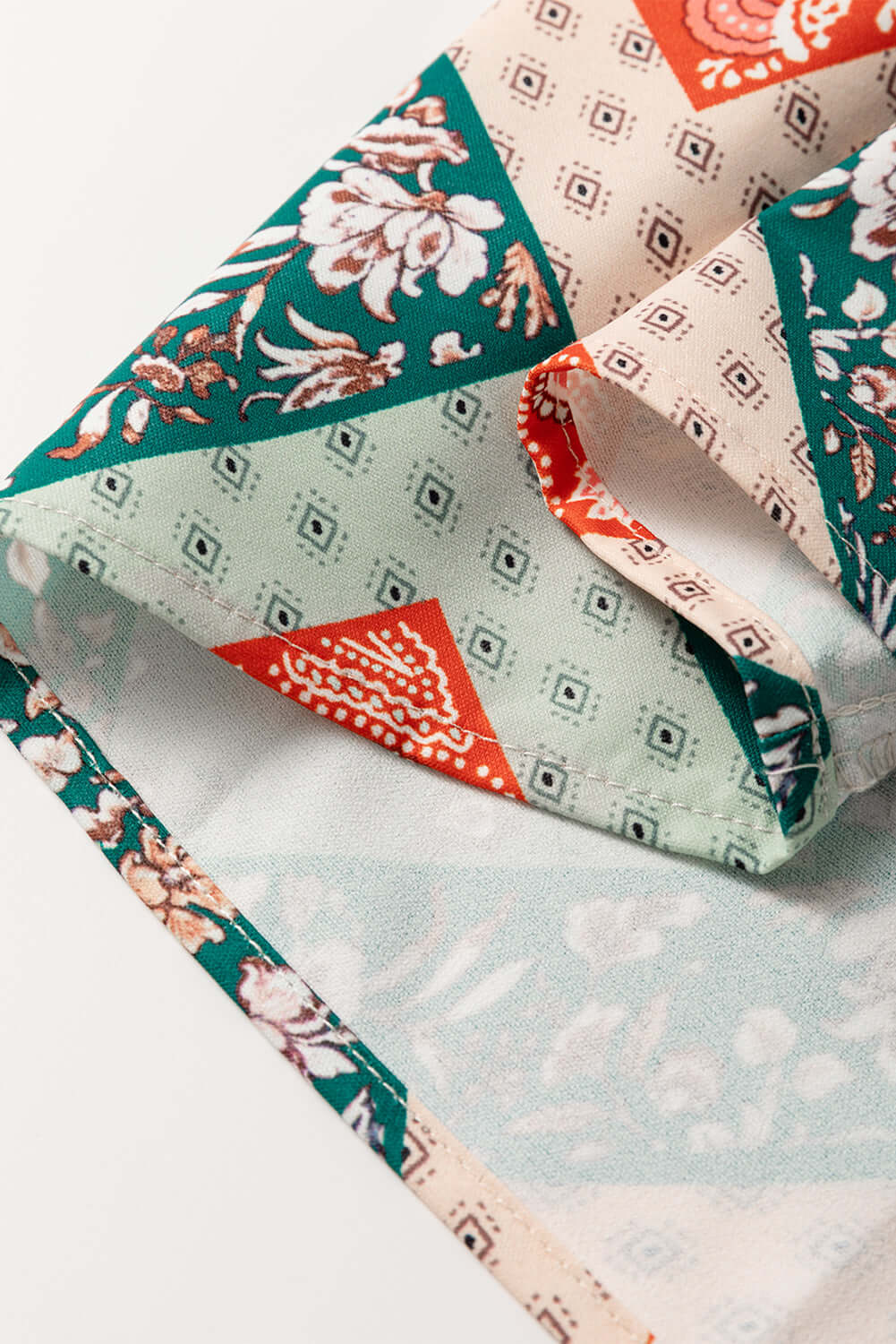 Close-up of the geometric patchwork design on the PATCHWORK POETRY TOP showcasing warm hues and floral patterns.