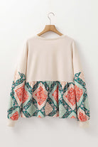 Back view of PATCHWORK POETRY TOP showcasing geometric patchwork design in warm colors and bubble sleeves.