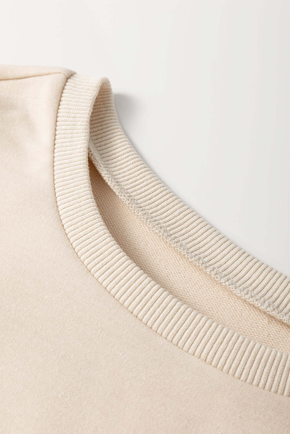 Close-up of the crew neckline of the PATCHWORK POETRY TOP, showcasing a soft, cozy fabric in neutral tones.