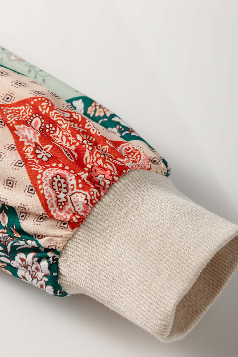 Close-up of the PATCHWORK POETRY TOP showing colorful patchwork sleeve design with textured cuff.