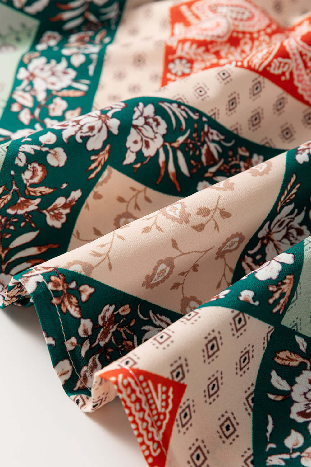 Close-up of the PATCHWORK POETRY TOP fabric featuring colorful geometric patchwork and floral designs.