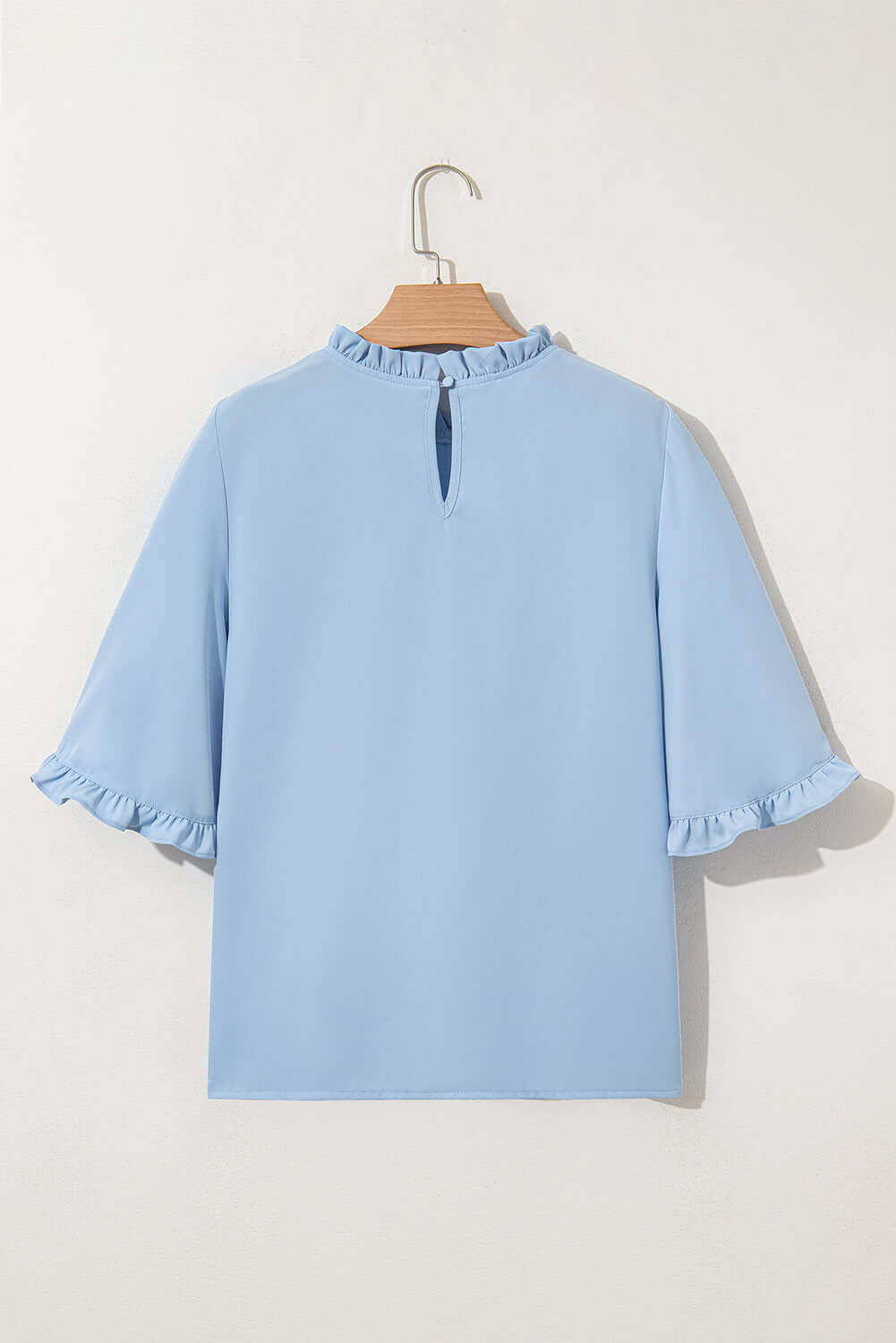 Back view of Frill Seeker Top in sky blue, featuring ruffled sleeves and neckline for a chic, feminine look.