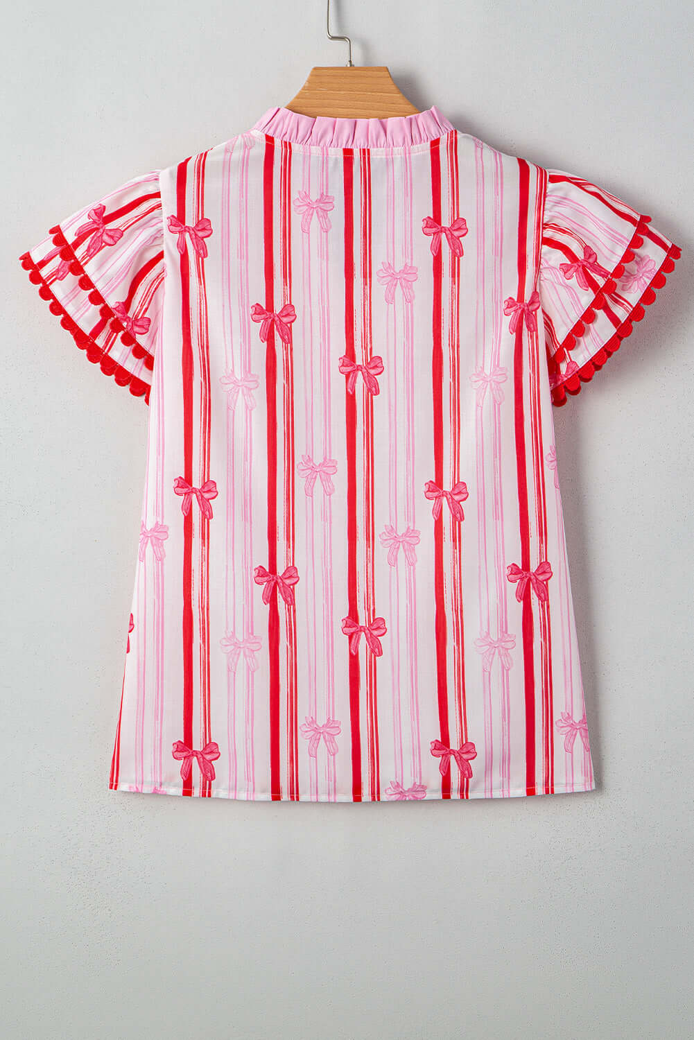 Back view of the Ribbon Reign Top featuring a striped bow print and ric-rac trim in pink and red.