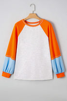 CITRUS CRUSH TOP featuring color block design with vibrant tangerine sleeves and soft sky blue cuffs on a light grey body.