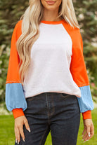 CITRUS CRUSH TOP showcasing vibrant tangerine sleeves and soft sky blue cuffs in a playful and stylish color block design.