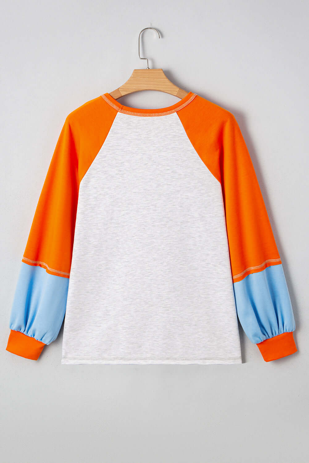 Back view of CITRUS CRUSH TOP featuring bold tangerine sleeves, soft sky blue cuffs, and a light grey body.