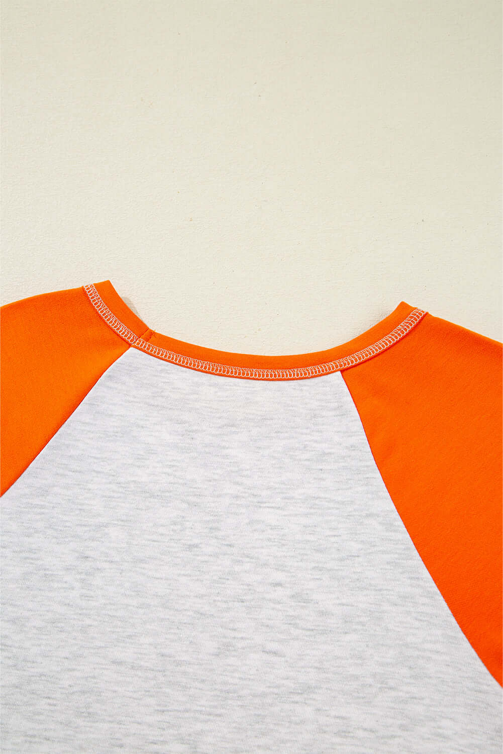 Back view of the CITRUS CRUSH TOP showing vibrant orange sleeves and light grey body, highlighting its color block design.