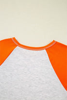 Back view of the CITRUS CRUSH TOP showing vibrant orange sleeves and light grey body, highlighting its color block design.