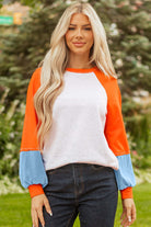 Model wearing CITRUS CRUSH TOP with bold tangerine sleeves and soft sky blue cuffs on a light grey body.