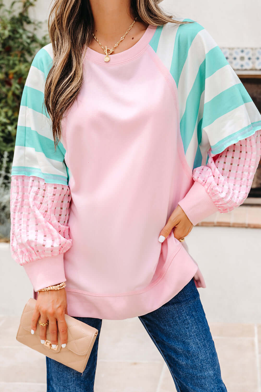 SWEET ESCAPE TOP featuring a pink pullover with striped sleeves and playful pastel colors for a chic, casual look.