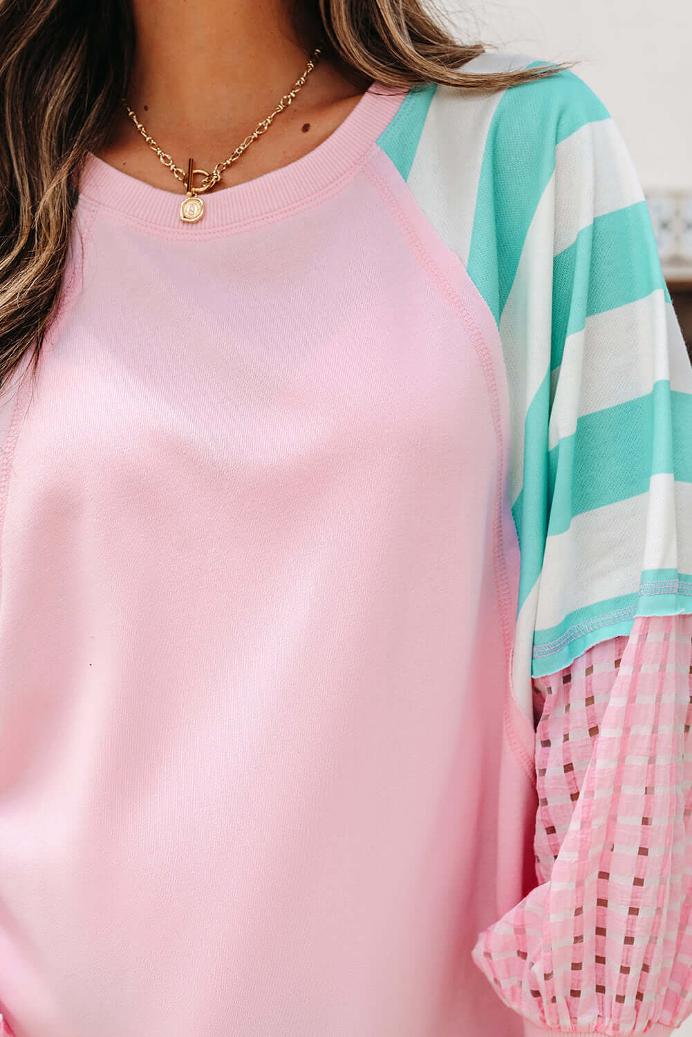 Close-up of a woman wearing the SWEET ESCAPE TOP featuring pastel striped colorblock design and loose fit.
