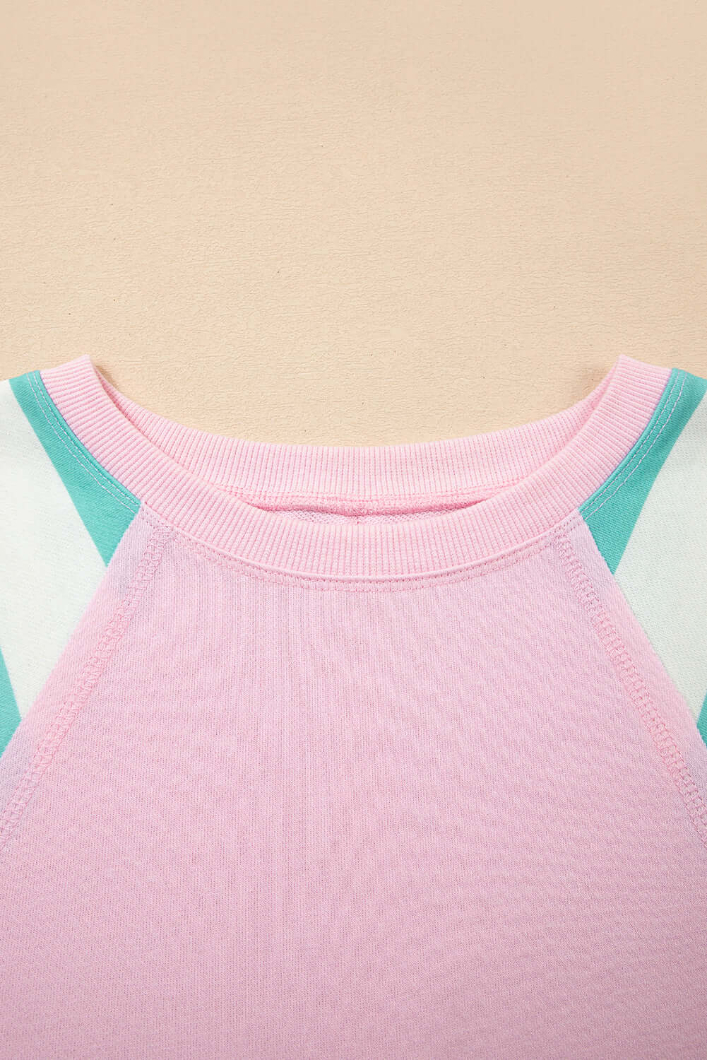 Close-up of the neckline of the SWEET ESCAPE TOP featuring pastel colorblock design and soft fabric texture.