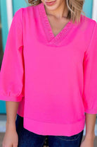 Model wearing GRACEFUL GLOW TOP (bright pink) featuring a frilled V-neckline and bracelet sleeves.