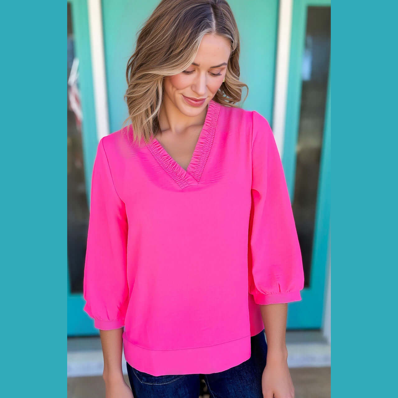 Model wearing GRACEFUL GLOW TOP (bright pink) with frilled V-neckline and bracelet sleeves.