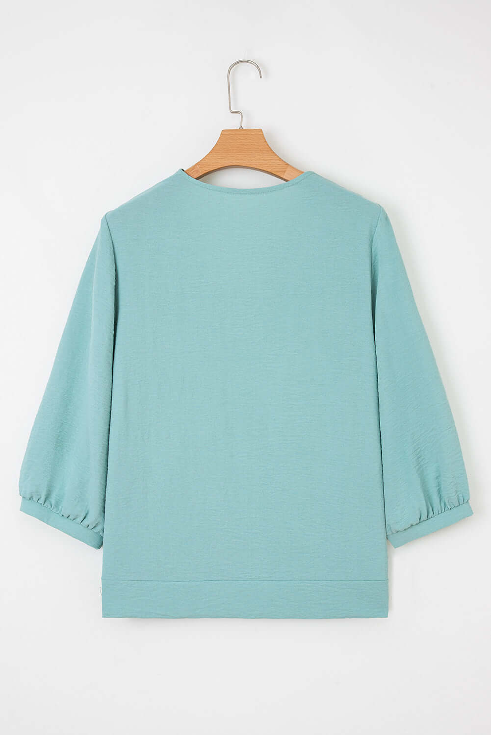 Back view of the GRACEFUL GLOW TOP (jade sea) featuring a chic design and elegant bracelet sleeves.