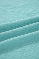 Close-up of crinkled fabric texture in jade sea, showcasing the material of the GRACEFUL GLOW TOP (jade sea).