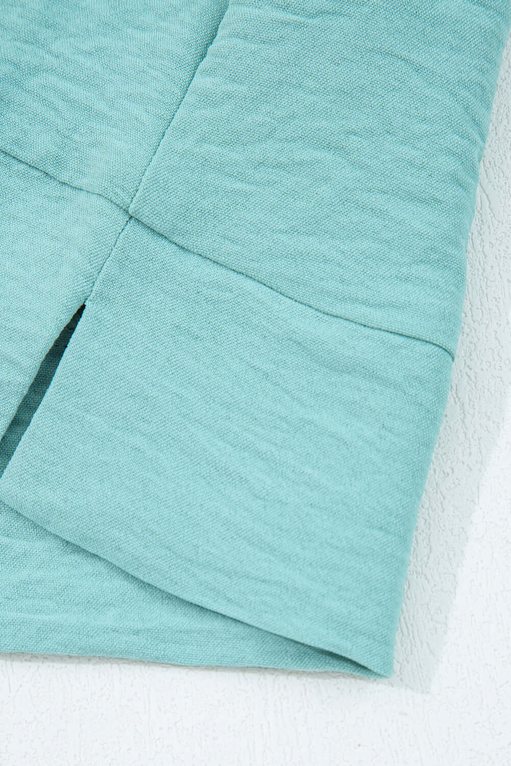 Close-up of the crinkled fabric of the GRACEFUL GLOW TOP (jade sea) showcasing its elegant texture and color.