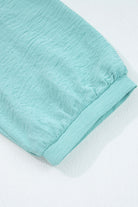 Close-up of the sleeve of the GRACEFUL GLOW TOP (jade sea) showcasing its crinkled fabric texture and elegant design.