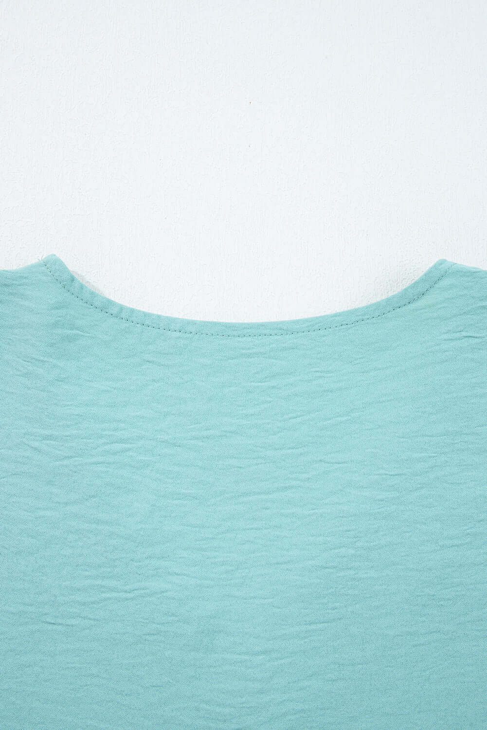 Back view of the GRACEFUL GLOW TOP (jade sea) showcasing the elegant neckline and textured fabric.