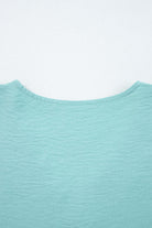 Back view of the GRACEFUL GLOW TOP (jade sea) showcasing the elegant neckline and textured fabric.