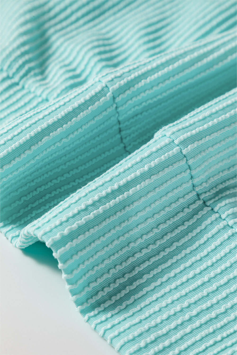 Close-up of the AQUA AVENUE TOP showcasing the textured ribbed fabric in a vibrant aqua color.