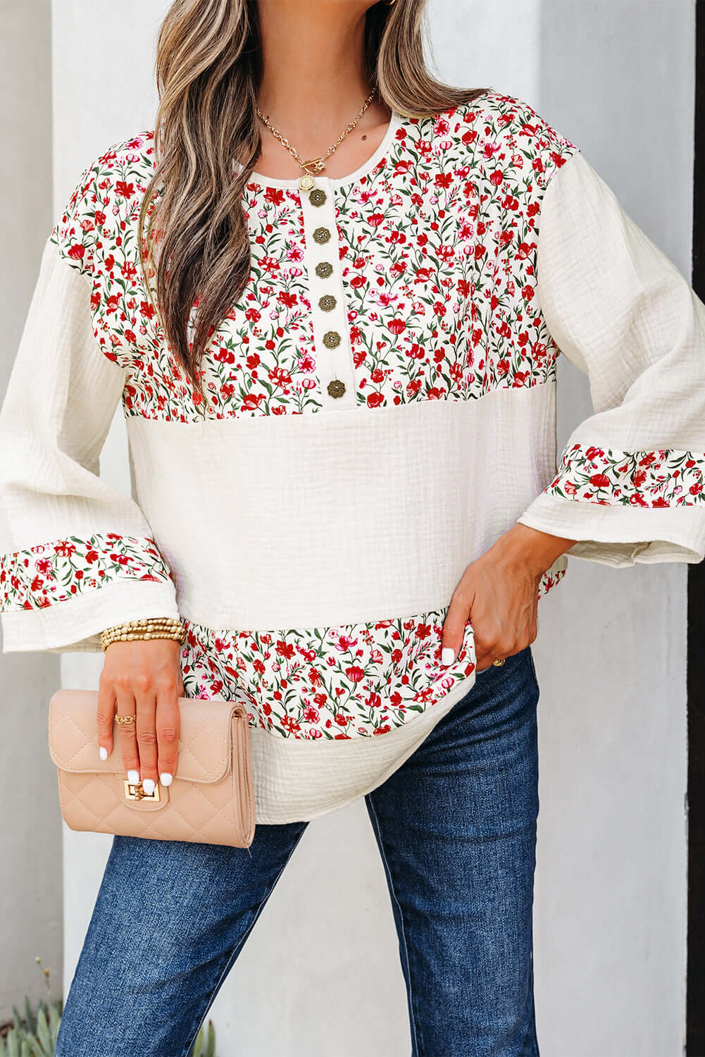 CROSSROADS CUTIE blouse featuring floral design, Henley button neckline, and 3/4 sleeves, styled with denim and a handbag.